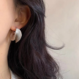 Elegant silver textured folding fan-shaped hoop earrings worn by a female model