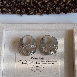 Macro view of silver layered shell texture earrings on a vintage fabric display