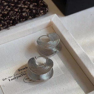 Detailed view of silver layered wave hoop earrings on a luxury display tray