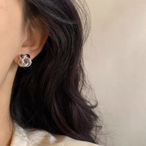 Elegant silver twisted knot stud earrings shown on ear for a minimalist jewelry look