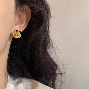 Detailed view of elegant gold twist knot earrings on model highlighting metallic texture