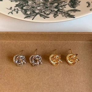 Detailed view of gold and silver twisted knot stud earrings on a kraft gift box