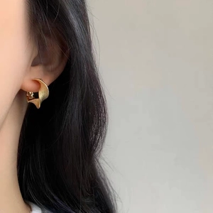 Close-up of golden twisted Mobius hoop earrings with textured finish on model