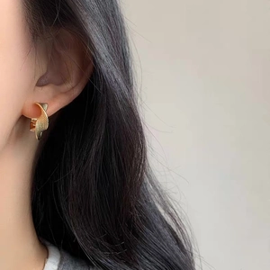 Detail of twisted Mobius gold hoop earrings with sandblasted metallic texture on model