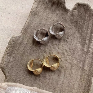 Detail of twisted Mobius loop earrings in gold and silver finish with textured surface