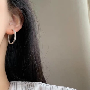 Elegant silver circle earrings with paved zircon stones worn by a model on grey background