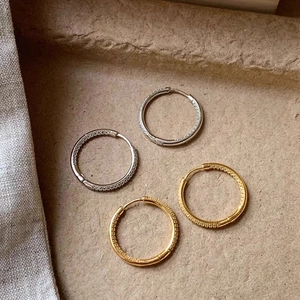 Minimalist gold and silver hoop earrings set with zirconia and engraved textures