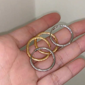 Macro detail of gold and silver hoop earrings with pave-set rhinestones held in hand