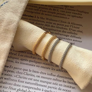 Detailed close-up of gold and silver pavé hoop earrings on a vintage fabric prop