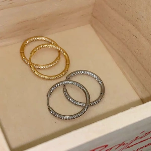 Detail of gold and silver pavé hoop earrings with shimmering rhinestones on wood