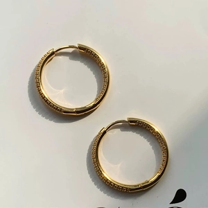 Macro detail of gold-plated hoop earrings featuring micro-pave white cubic zirconia