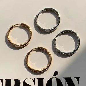 Detailed view of four crystal-encrusted gold and silver hoop earrings on a magazine background