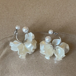 Elegant floral pearl hoop earrings with layered white petals on a textured glass tray