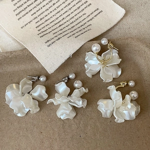 Elegant French style white flower earrings with pearls and gold hooks on textured background