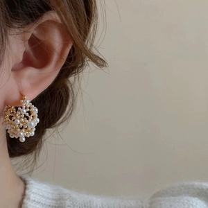 Elegant pearl cluster hoop earrings with golden base shown on a model in profile view