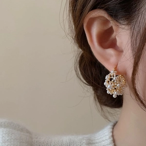 Elegant French-style gold mesh earrings with clusters of white pearls on a model