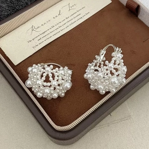 Detail of hollow woven pearl spherical earrings on a brown velvet jewelry box liner