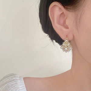 Boucles d'oreilles panier de fleurs dorées avec perles blanches sur mannequin