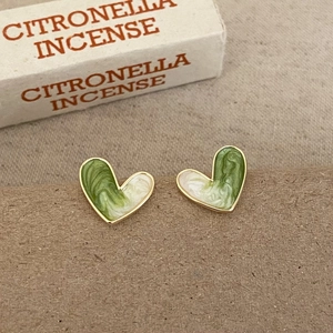 Macro shot of green heart-shaped enamel studs with marbled texture on fabric background