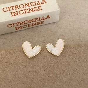 Pink marbled heart earrings with gold trim on a minimalist textured background