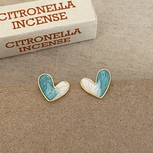 Detailed close-up of heart-shaped gold studs with blue and white marbled enamel inlay