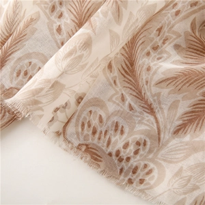 Close-up of soft voile scarf featuring brown floral feather prints and frayed tassel edges