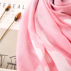 Detailed close-up of pink sun protection scarf with white floral print and soft texture