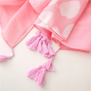 Close-up of pink sun protection scarf with white heart patterns and delicate tassels