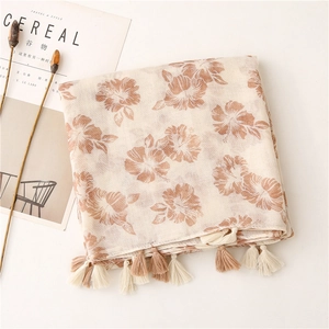Detailed close-up of hibiscus floral print and cotton tassels on a linen-feel scarf