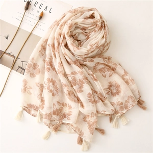 Detail of floral print scarf with soft texture and tassels on minimalist background