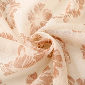 Detailed macro texture of a lightweight beige linen scarf with brown floral prints