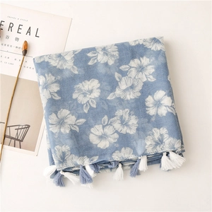 Close-up of blue floral cotton scarf with detailed two-tone tassels and soft fabric texture
