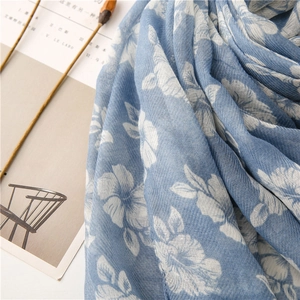 Close-up of sky blue cotton linen scarf with white floral print texture and soft fabric