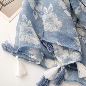 Detailed close-up of blue floral cotton linen scarf with elegant tassel trim edges