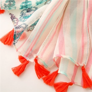 Detail of striped floral voile scarf featuring vibrant orange fringe tassels and soft texture