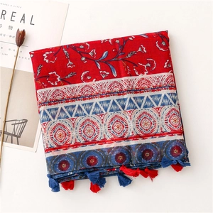 Close-up of ethnic floral cotton shawl with red and blue tassels and woven texture