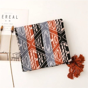 Detail of geometric printed scarf with orange tassels and soft cotton linen texture