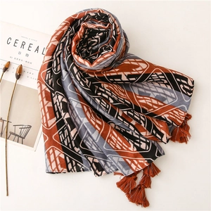 Detail of blue geometric patterned scarf featuring orange contrast and tassel edges