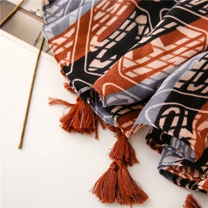 Detail of blue abstract cotton shawl featuring orange fringe tassels and woven texture