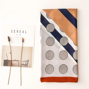 Detail of color-block scarf with geometric patterns and orange hem on white background
