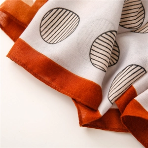 Detail of linen scarf with orange border and striped polka dot pattern texture