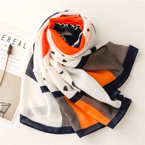 Detail of cotton linen scarf with geometric orange and blue patterns near a magazine