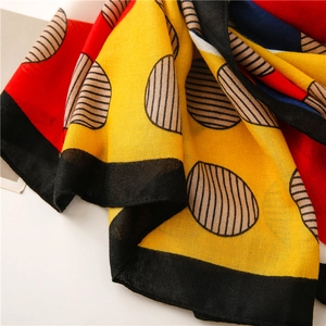 Detailed macro shot of color-blocked scarf fabric with bold yellow and red polka dots