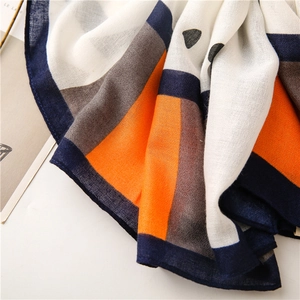 Macro shot of geometric block patterned scarf showing soft woven texture and orange blue tones