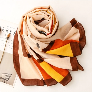 Detail of soft chiffon scarf featuring bold geometric blocks in orange and beige tones