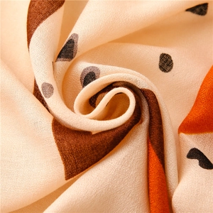 Macro texture of a lightweight beige shawl featuring orange and brown geometric patterns
