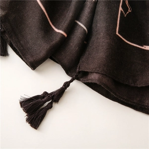 Gros plan sur une écharpe en lin marron avec motifs dorés et détails de franges