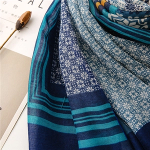 Detail of bohemian geometric flower patterns on a soft navy and orange linen shawl
