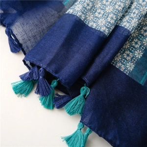 Detailed view of blue geometric pattern scarf featuring handmade cyan and navy tassels