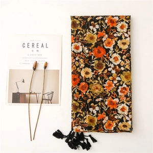 Cotton linen feel scarf with orange floral prints and black tassels on white background